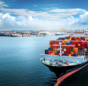 Container ship docked at a busy port under a bright sky
