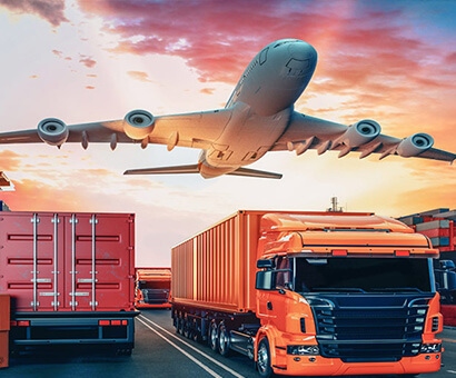 Cargo plane departing above a loaded freight truck at sunset